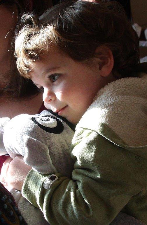 A toddler hugging Trouble the Dog in the sunlight
