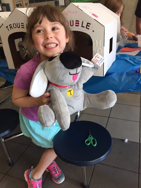 A smiling little girl holding Trouble the Dog